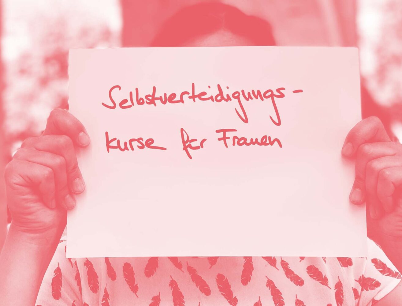 Frau hält Zettel mit Aufschrift: Selbstverteidigungskurse für Frauen