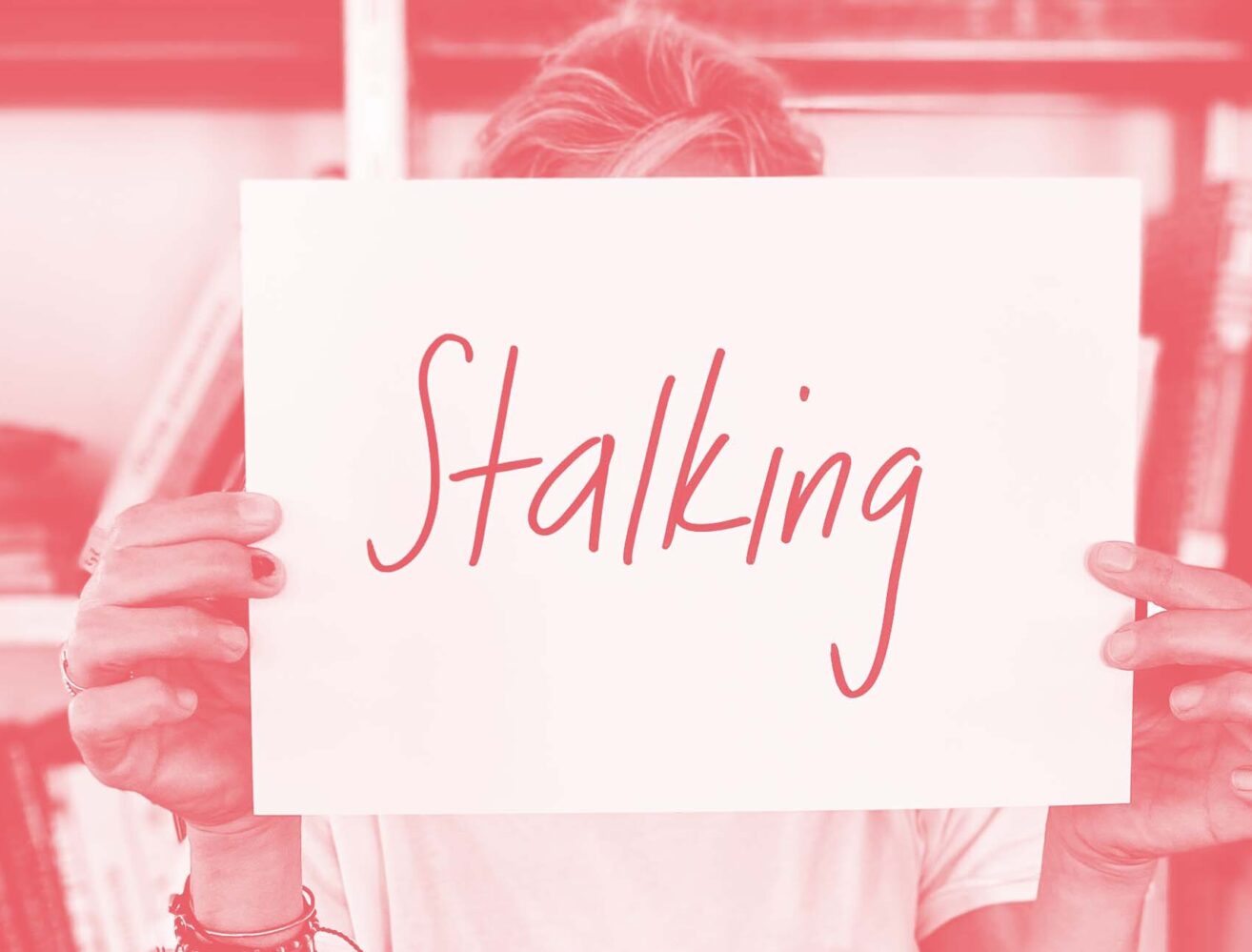 Frau hält Zettel mit Aufschrift: Stalking